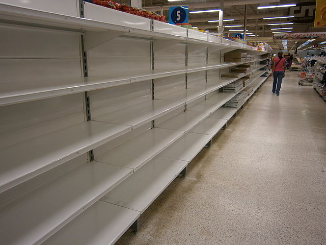 Empty shelves in a Venezuelan supermarket. Via Wikimedia Commons