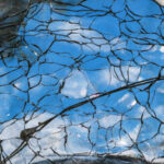 Broken glass reflecting sky.